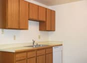 Thumbnail 7 of 13 - A kitchen with wooden cabinets and a white dishwasher.