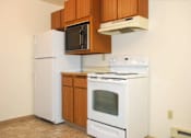 Thumbnail 8 of 13 - A white refrigerator and oven in a kitchen with brown cabinets.