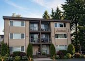 Thumbnail 16 of 16 - The image shows a multi-story apartment building named "Lorimer 1" with a parking lot in front and trees in the background.