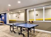 Thumbnail 13 of 14 - A room with a blue and yellow wall and a ping pong table.