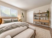 Thumbnail 4 of 14 - A bedroom with a large bed and a wooden shelf.