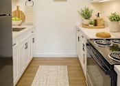Thumbnail 2 of 17 - A kitchen with a black fridge and stove top oven.