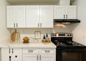 Thumbnail 3 of 17 - A kitchen with white cabinets and a black stove top oven.