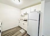 Thumbnail 7 of 17 - A white refrigerator is in a kitchen with white cabinets.
