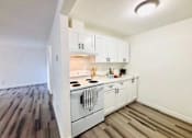 Thumbnail 6 of 17 - A kitchen with white cabinets and a wooden floor.