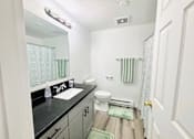 Thumbnail 5 of 17 - A bathroom with a sink, toilet, and a mirror.