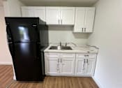 Thumbnail 11 of 17 - A black refrigerator is in a kitchen with white cabinets.