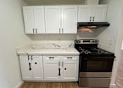 Thumbnail 12 of 17 - A kitchen with white cabinets and a black stove top oven.