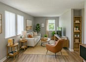 Thumbnail 5 of 13 - A living room with a white couch, a brown chair, and a television.