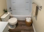 Thumbnail 6 of 17 - A white toilet sits next to a white bathtub in a small bathroom.