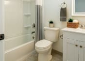 Thumbnail 7 of 16 - A white toilet sits in a bathroom next to a white sink.