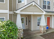 Thumbnail 14 of 16 - A house with a red door and a stone pillar in front of it.