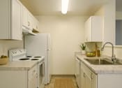 Thumbnail 3 of 16 - A kitchen with white appliances and cabinets.