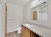 Thumbnail 11 of 14 - A small bathroom with a toilet, sink, and mirror.