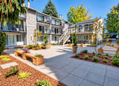 Thumbnail 17 of 18 - A courtyard with a concrete floor and a variety of plants and trees.