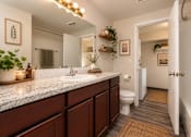 Thumbnail 10 of 18 - A bathroom with a marble countertop and wooden cabinets.