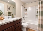 Thumbnail 5 of 18 - A bathroom with a white toilet, a sink, and a shower.