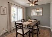 Thumbnail 4 of 18 - A dining room with a table set for two and a ceiling fan.