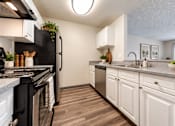 Thumbnail 3 of 18 - A kitchen with black appliances and white cabinets.