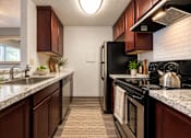 Thumbnail 9 of 18 - A kitchen with dark wood cabinets and a black refrigerator.