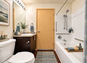 Thumbnail 8 of 18 - A bathroom with a toilet, sink, and bathtub.