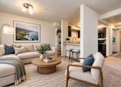 Thumbnail 3 of 18 - A living room with a sofa, a chair, a coffee table, and a painting on the wall.