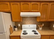 Thumbnail 16 of 18 - A white stove in a kitchen with wooden cabinets.