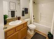 Thumbnail 5 of 18 - A bathroom with a toilet, sink, and mirror.