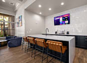 Thumbnail 28 of 42 - a kitchen with a counter and chairs and a tv on the wall