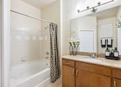 Thumbnail 13 of 42 - A bathroom with a white tub, a sink, and a mirror.