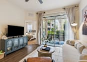 Thumbnail 9 of 42 - A living room with a television, sofa, and sliding glass doors.