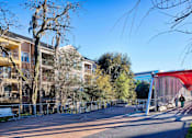 Thumbnail 39 of 42 - a street with buildings and a red bridge