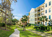Thumbnail 38 of 42 - a walkway between apartment buildings with palm trees