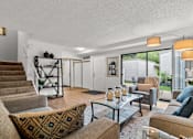 Thumbnail 3 of 15 - A living room with a brown couch and a glass table.