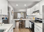 Thumbnail 6 of 15 - A modern kitchen with white cabinets and stainless steel appliances.