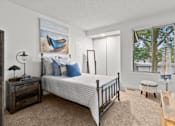 Thumbnail 5 of 16 - A bedroom with a bed, nightstand, and a window with a view of trees.