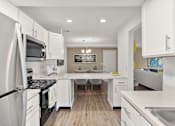 Thumbnail 2 of 16 - A modern kitchen with white cabinets and stainless steel appliances.