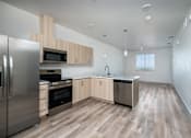 Thumbnail 4 of 16 - A modern kitchen with wooden floors and stainless steel appliances.
