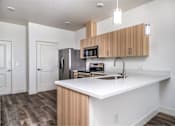 Thumbnail 5 of 16 - A kitchen with a white counter top and wooden cabinets.