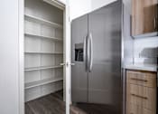 Thumbnail 7 of 16 - A modern kitchen with a stainless steel refrigerator and wooden cabinets.