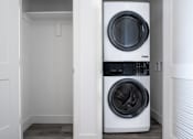 Thumbnail 9 of 16 - A white front load washing machine in a small laundry room.