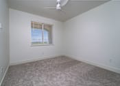 Thumbnail 12 of 16 - A room with a ceiling fan and carpeted floor.
