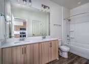 Thumbnail 14 of 16 - A modern bathroom with a wooden vanity and white countertop.