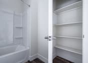 Thumbnail 15 of 16 - A white bathroom with a white bathtub and a white walk in closet.