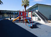 Thumbnail 19 of 20 - A playground with a slide and a palm tree.