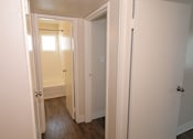 Thumbnail 6 of 20 - A hallway with white doors and a wooden floor.
