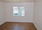 Thumbnail 10 of 20 - A room with a window and wooden floors.