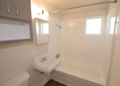 Thumbnail 7 of 20 - A white bathroom with a tub, sink, and mirror.