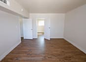 Thumbnail 4 of 20 - A room with wooden floors and white walls with three doors.
