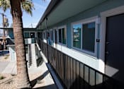 Thumbnail 16 of 20 - A balcony with a black railing and a palm tree in front of a house.